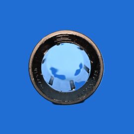 Close-up of a camera lens reflecting blue sky, set against a solid blue background.