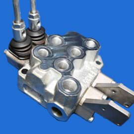 Close-up of a metal hydraulic valve block with threaded ports and fittings against a blue background