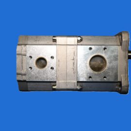 Metallic industrial valve or hydraulic block with bolts and circular ports, set against a blue background.