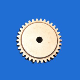 HH94 – DEMI-ACCOUPLEMENT TAILLE 28 2 Partial view of a beige gear with teeth at the bottom edge against a solid blue background.
