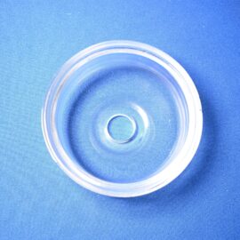 Close-up of a transparent circular glass jar lid resting on blue fabric top view