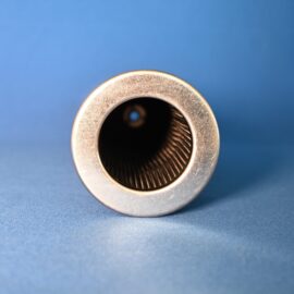 Close-up of a silver metal cylindrical object (lens) with a dark interior and visible internal ridges against a blue background.