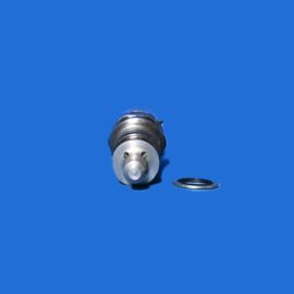 Close-up of a metallic valve or connector part on a bright blue background, with a small ring placed nearby.