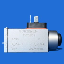 Close-up of a metal electrical terminal on a gray industrial device against a blue background, top prongs visible.