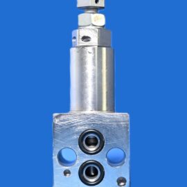 HH249 – LIMITEUR DE PRESSION VALVE DE SEQUENCE- 7700 0047-00HW 2 Close-up of a metallic hydraulic valve block with several round ports and a protruding rod against a solid blue background of the image's background space.