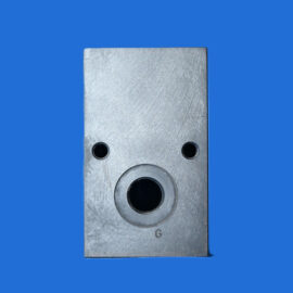 Close-up of a brushed metal plate with two small round holes and a large circular hole against a blue background.