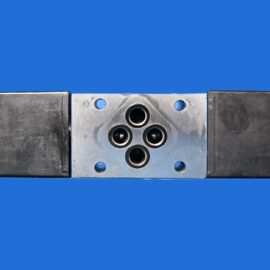 Metal hydraulic valve block with four ports, black end caps, on a blue background.