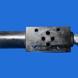 Metal hydraulic valve block with multiple round ports attached to a cylindrical actuator against a solid blue background, side view.