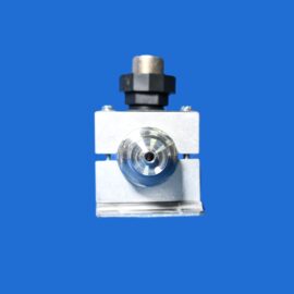 Close-up of a metal valve assembly with a black plastic cap atop a square block, against a solid blue background.