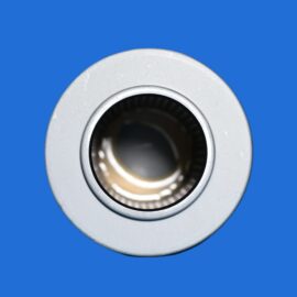 Close-up of a silver metal bearing/ring against a bright blue background, showing the inner bore and outer race edges.