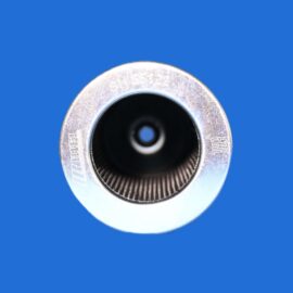 Close-up of a metal cylindrical object with a black inner bore on a blue background, photographed at an angle.