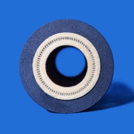 Close-up of a black sanding disc with a beige inner ring, set against a vivid blue background