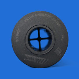 Close-up of a black circular spool against a bright blue background, showing its inner ring and cross-shaped opening.