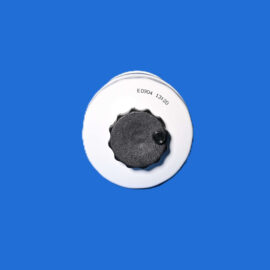 Close-up of a white circular knob with a black, textured dial on a blue background.