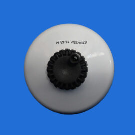 Close-up of a white circular device with a black knurled knob in the center on a blue background.