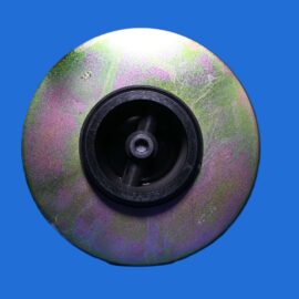 Close-up of a circular abrasive grinding wheel with a colorful iridescent surface and black center against a blue background.