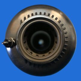Close-up of a circular metal lens or bearing assembly against a blue background, showing inner rings and gear-like notches.