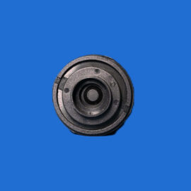 Close-up of a black, circular mechanical part with concentric rings on a solid blue background with textured edges.