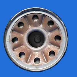 Close-up of a rusted metal car wheel rim against a blue background