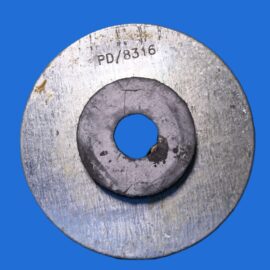 Close-up of a worn metal washer with a large outer ring and inner hole, stamped PD/8316, on a solid blue background.